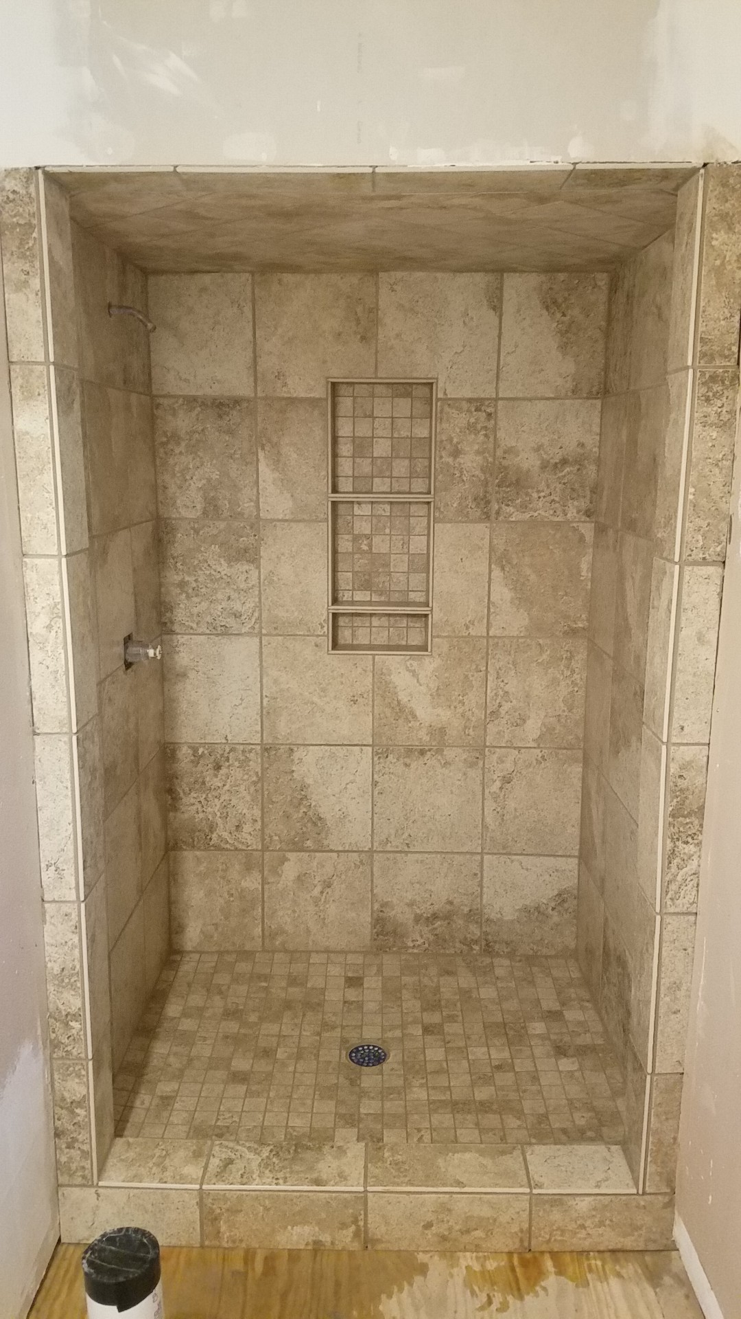 Newly tiled walk-in shower with three-shelf recessed niche and mosaic tile floor